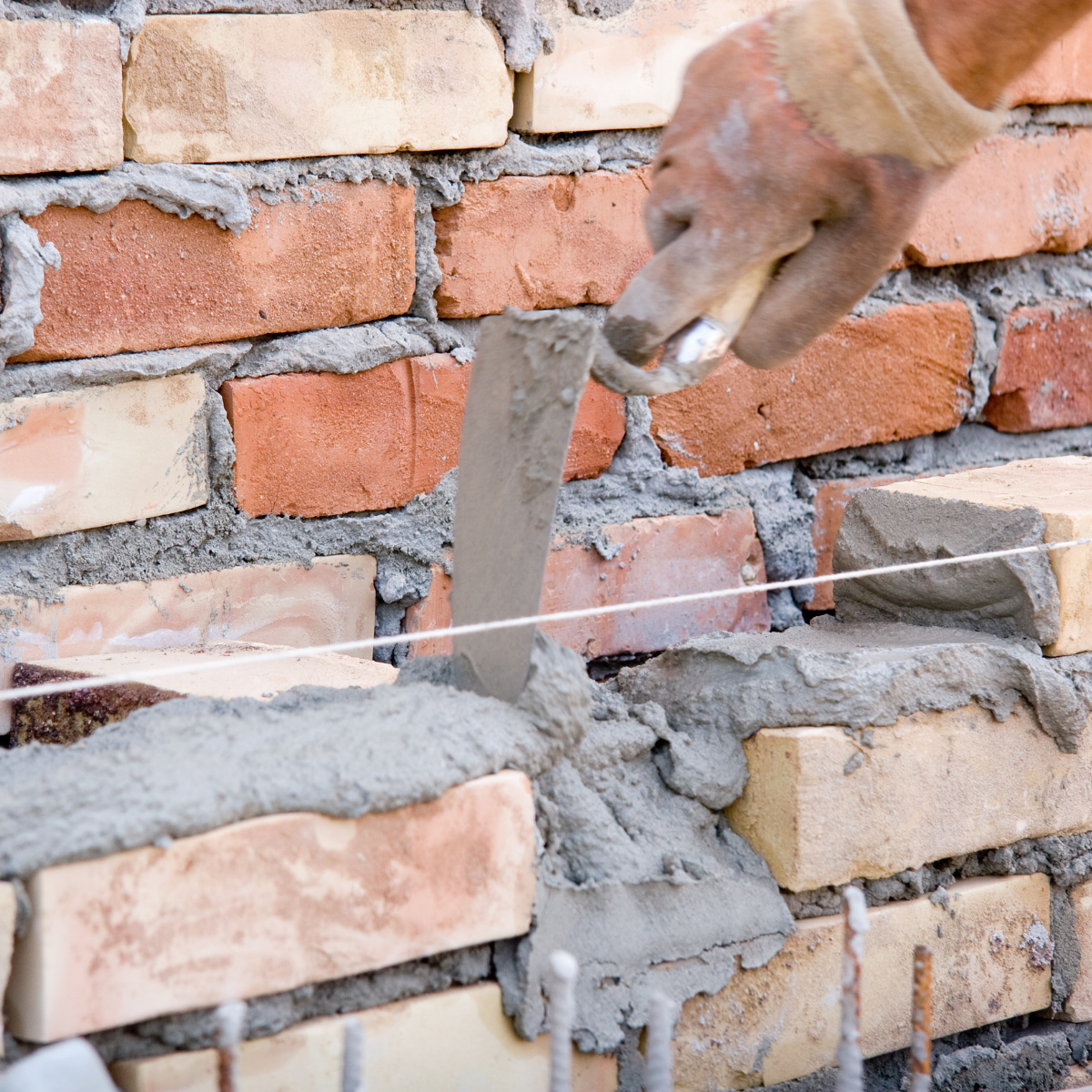 Laying structural CMU blocks on a job site managed by experienced commercial masonry contractors near me.